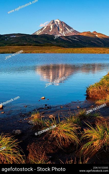 Autumn volcanic landscape, evening view of cone Vilyuchinsky Volcano and reflection of mountains peak in beautiful alpine lake