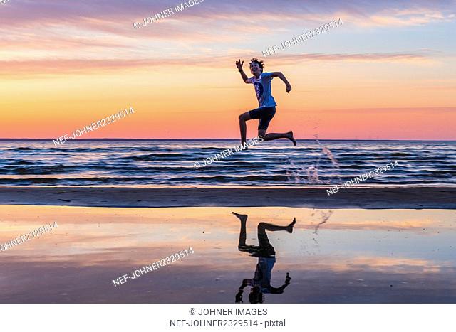 Boy jumping on beach at sunset