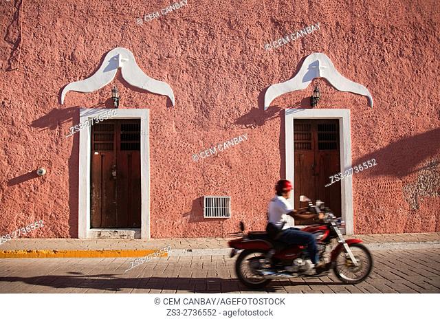 Motorcyclist in front of the colonial buildings in Calzada De Los Frailes at the historic center of the town, Valladolid, Yucatan Province, Mexico