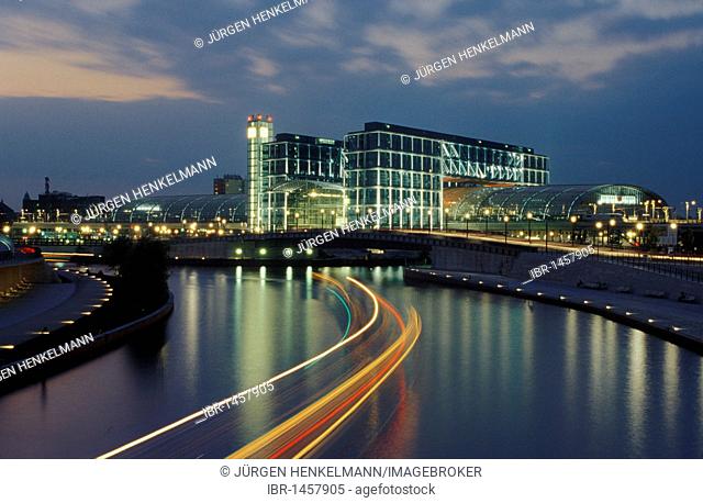 Berlin central station at night, by architects Gerkan, Marg and Partner, with excursion boat, the Spree river and the promenade at the Ludwig-Erhard-Ufer