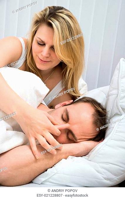 Happy Woman Is Holding Husband's Nose In Bedroom