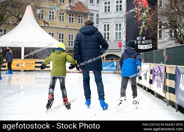02 January 2022, Lower Saxony, Brunswick: A man and two children skate on the ""Eiszauber"" ice rink on Kohlmarkt. At an unusually mild 14 degrees outside...