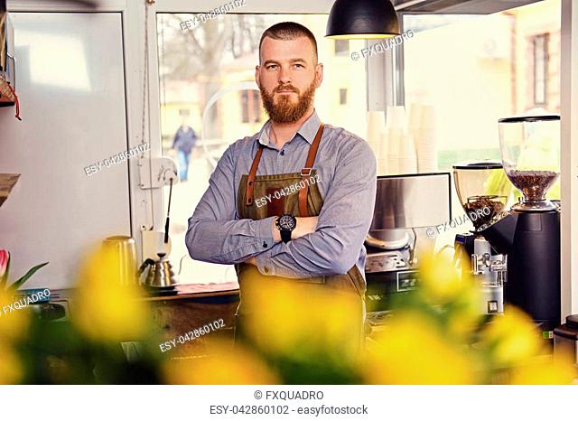 Portrait of bearded redheads seller in a small coffee house