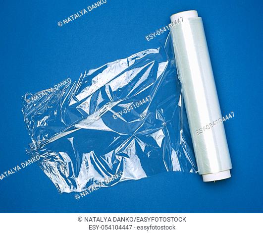 big roll of wound white transparent film for wrapping food, dark blue background, top view