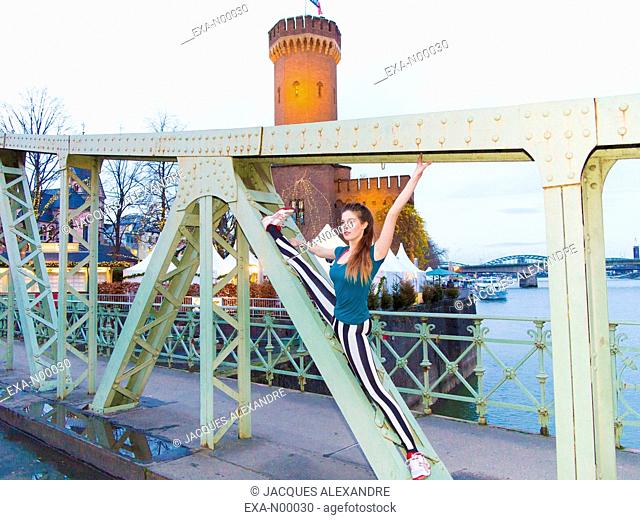 woman doing urban yoga exercises on a bridge at night with the Rhine river in the background