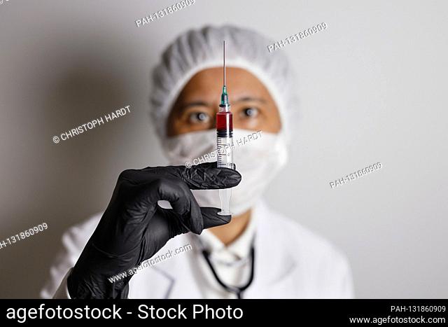 A virologist poses with a syringe for vaccination versus the corona virus (symbol photo with model) | usage worldwide. - Nuremberg/Bayern/Deutschland