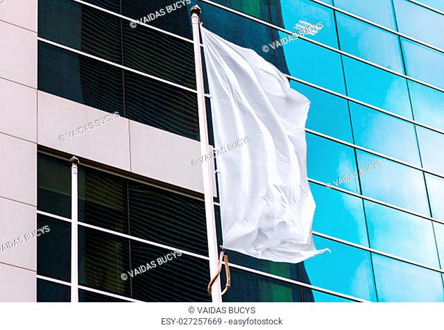 White flag waving in the wind with office building in the background. Perfect mockup to add any logo, symbol or sign