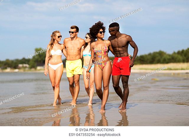 mixed race couple walking along beach with friends