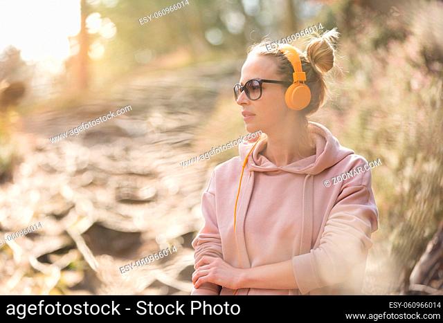 Portrait of beautiful sports woman wearing sunglasses, hoodie and headphones during outdoors training session. Healthy lifestyle image of young caucasian woman...