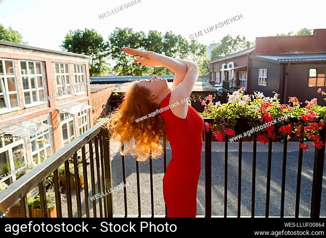 Woman with eyes closed stretching on balcony