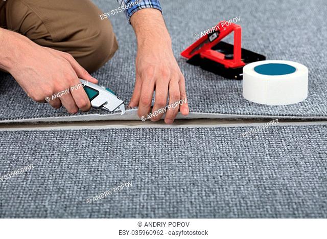 Close-up Of Carpenter Hand's Laying Carpet Using Cutter