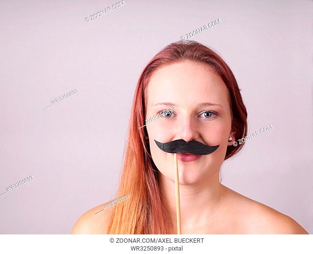 young woman holding a fake moustache on a stick to her face
