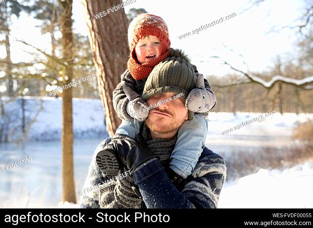 Father carrying son on shoulder during winter