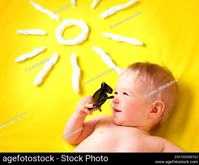 little boy with sunglasses and sun shape on yellow blanket