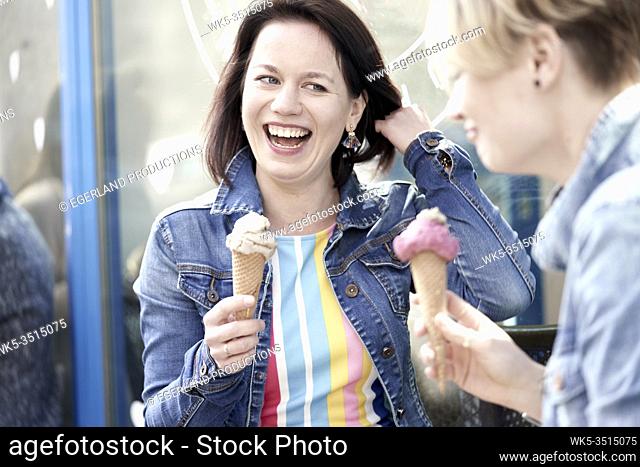 Two happy female friends eating vegan dairy-free and sugar-free ice cream cone made with cashew nuts and dates