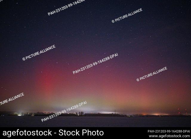 01 December 2023, Brandenburg, Lietzen: A reddish aurora borealis shines over the landscape in East Brandenburg in the evening