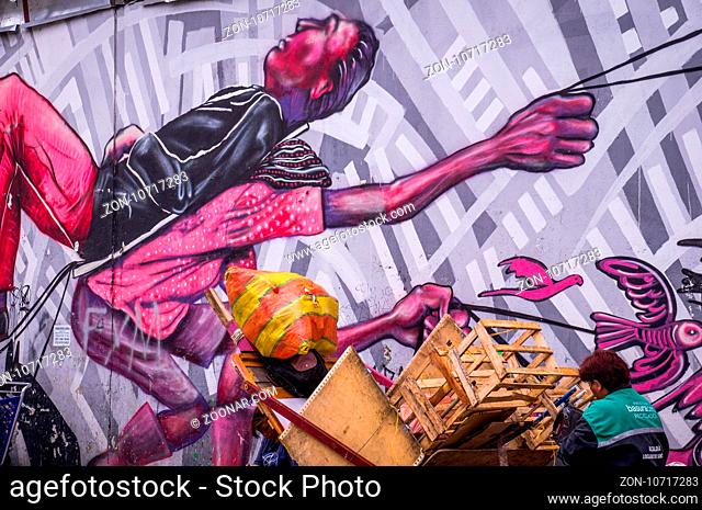 Bogota, Colombia on December 14, 2015: Wall covered in anti-capitalistic street art by artist Guache in La Candelaria neighborhood of Bogota showing a poor...