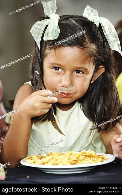 Young girl eating pasta