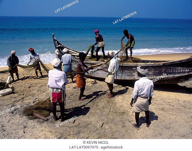 Kadaloram beach. Fishermen spreading nets to dry on sand. Local wooden dugout boat