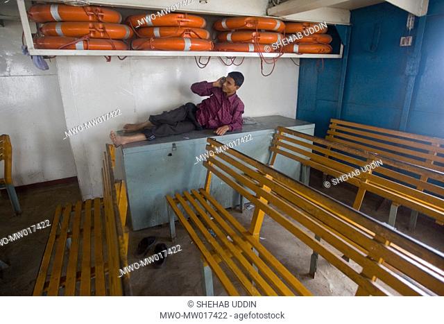 A young man is using a mobile phone in a public ferry that is crossing the Padma River Bangladesh November 05, 2008