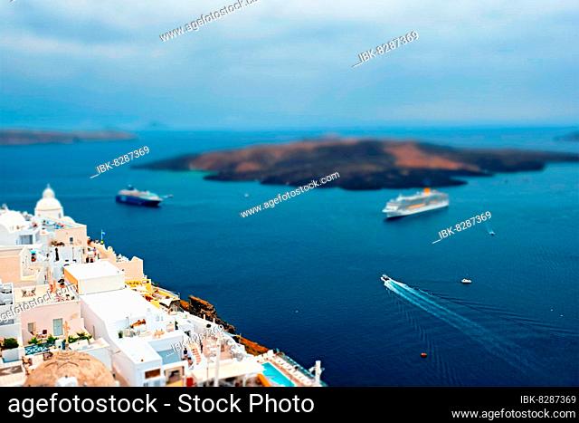 View of Fira Greek town with traditional white houses on Santorini island with cruise ships in sea Santorini, Greece Toy camera tilt shift miniature effect