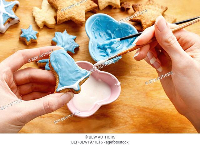 Decorating gingerbread cookies with blue and white icing. Steps of making biscuits