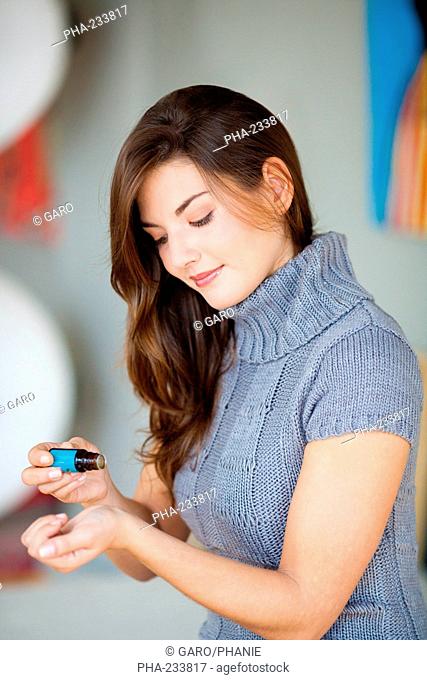 Woman applying essential oil on her skin