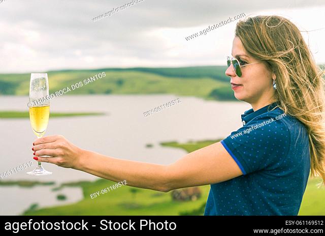 Young woman holding glass of sparkling (champagne)