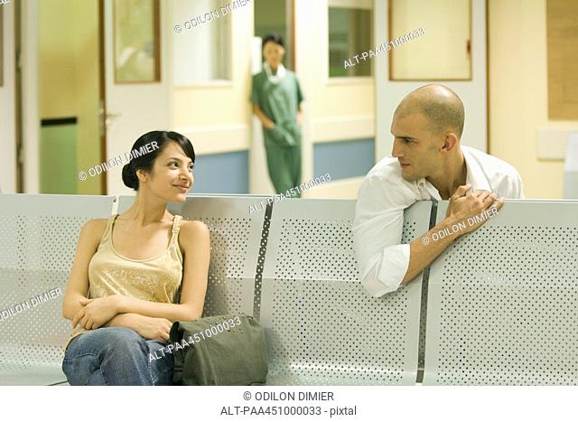 Two adults sitting in hospital waiting room, chatting