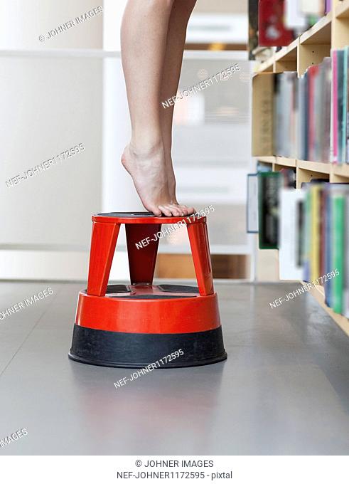 Tiptoe feet on stool in library