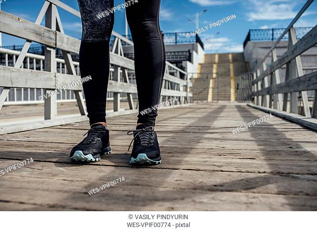 Legs of athletic woman standing on a pier