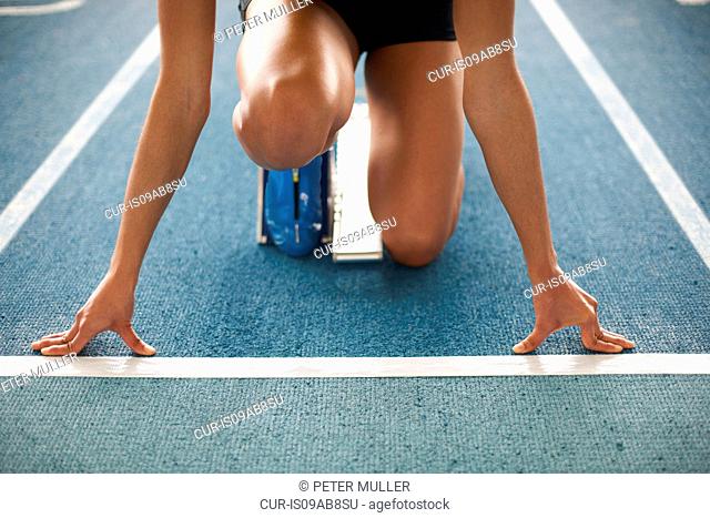 Young female athlete on starting blocks, close up