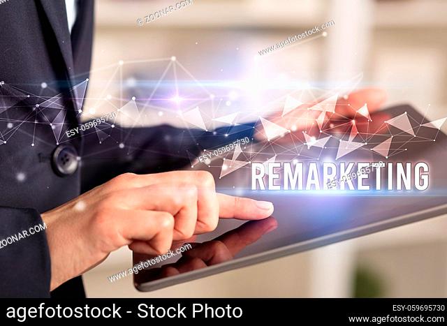 Close up hands using tablet with REMARKETING inscription, modern business technology concept