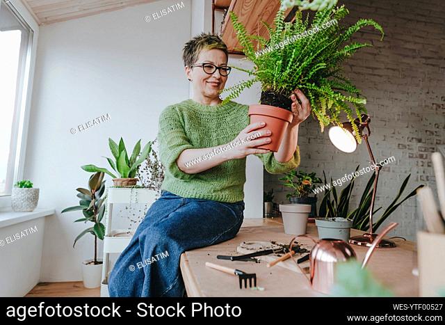 Smiling mature woman planting at home