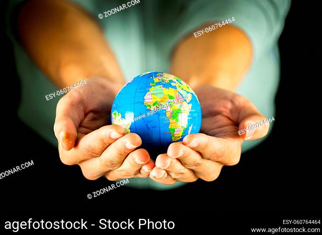 Male hands holding the Earth globe on black background