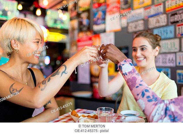Young women friends taking alcohol shots in bar