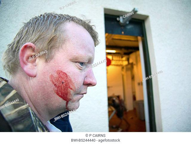 portrait of a stalker with blood on the cheek in front of a station where the shot animals are carved up, United Kingdom, Scotland, Sutherland