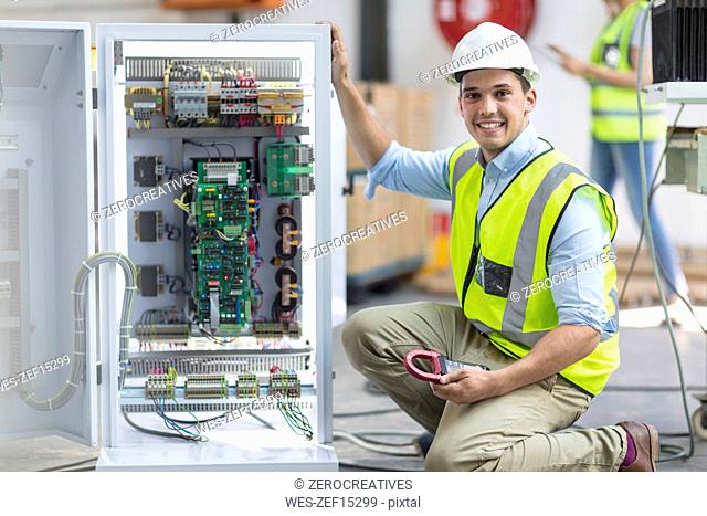 Portrait of smiling technician working on a box with circuit boards