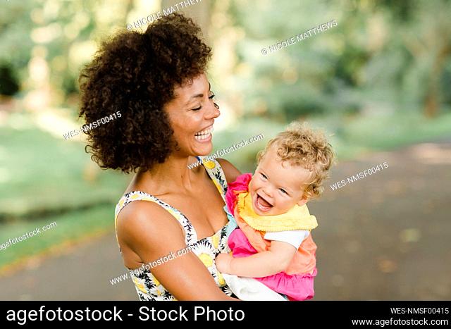 Cheerful mother holding baby while standing at park