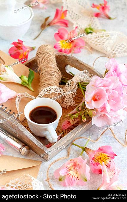 Coffee cup, rope and pink flowers on a tray on white table close up. Romantic breakfast, Spring and valentines day concept