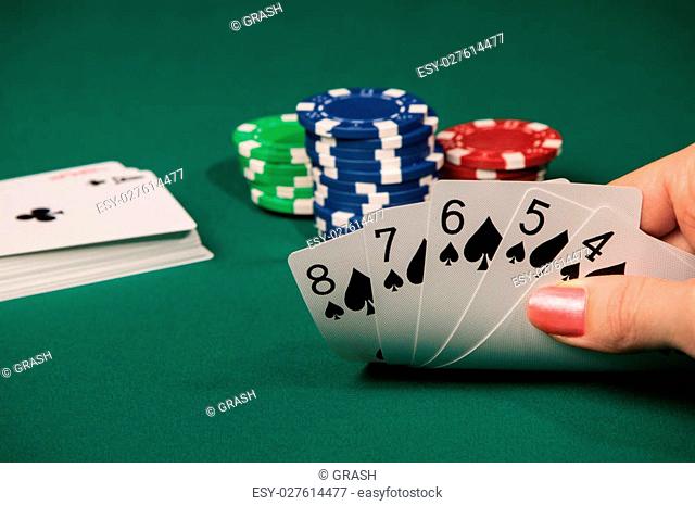 A female hand lifts the cards from the poker table with a combination of five consecutive peak