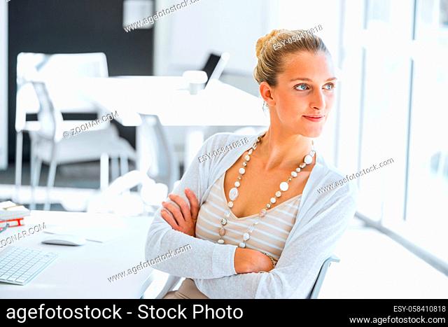 Attractive young woman sitting at desk and looking away