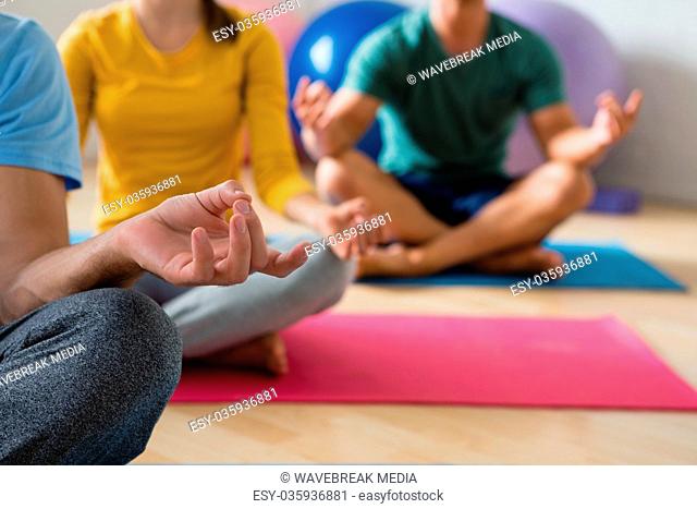 Midsection of yoga instructor with students meditating in lotus position