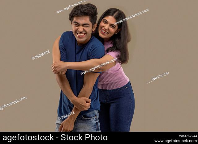 A BROTHER AND SISTER PLAYFULLY POSING IN FRONT OF CAMERA