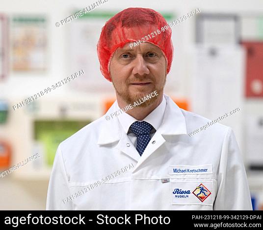 18 December 2023, Saxony, Riesa: Michael Kretschmer (CDU), Minister President of Saxony, wears a hairnet and a smock at the inauguration of a new production...