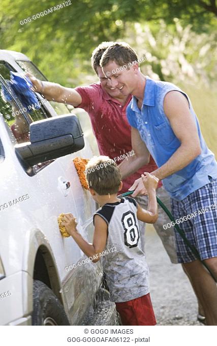 Gay couple washing the car with their son