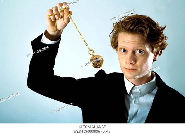 Portrait of young man swinging golden pocket watch