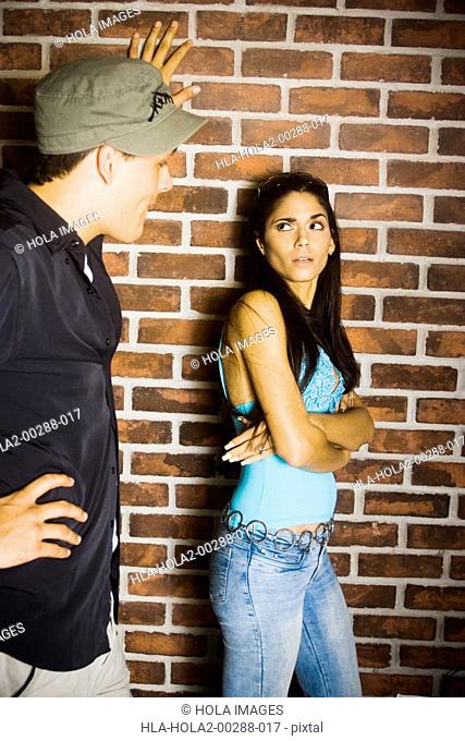 Young man and woman in front of brick wall