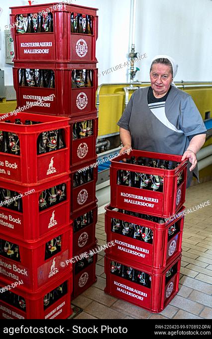 14 April 2022, Bavaria, Mallersdorf-Pfaffenberg: Sister Doris, brewmaster and nun at the Mallersdorf monastery, stands behind beer crates in the monastery...