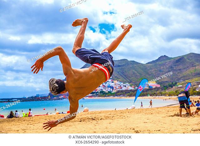 young male doing martial arts tricking sports on the beach